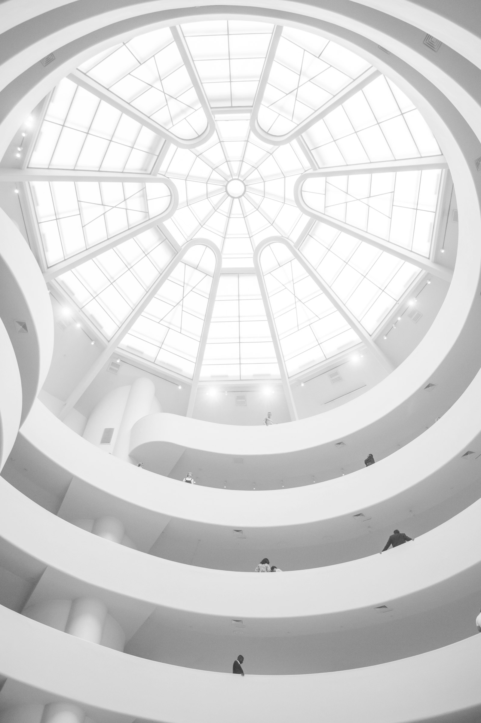 A calm white architectural atrium with spiral balconies beneath a glass dome
